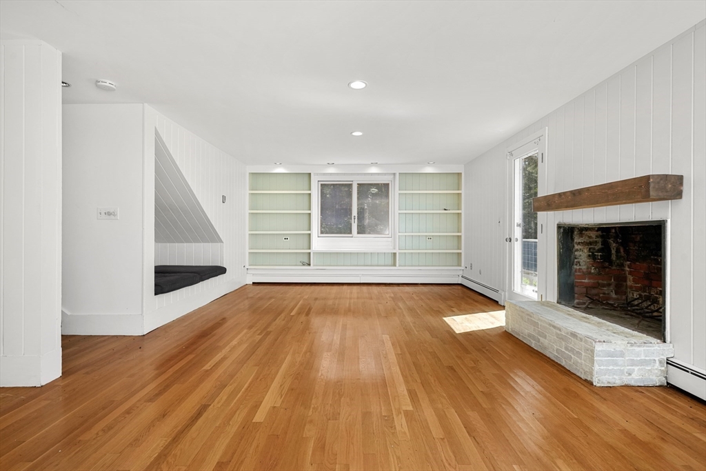 188 Country Drive, Unit 188 Weston, MA 02493 - Photo 9 of 21 an empty room with wooden floor and fireplace