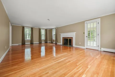 a view of empty room with wooden floor and fireplace
