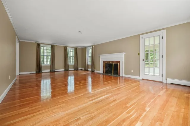 a view of empty room with wooden floor and fireplace