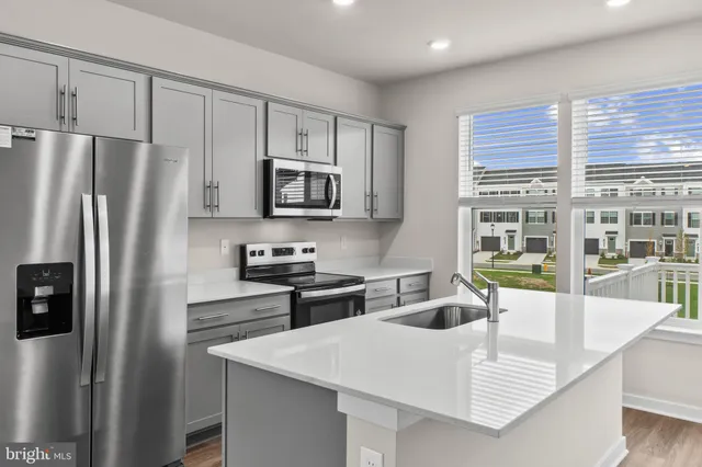 a kitchen with kitchen island a stove a sink a microwave a counter space and cabinets
