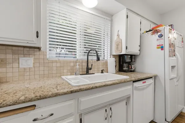 a kitchen with granite countertop white cabinets and white appliances