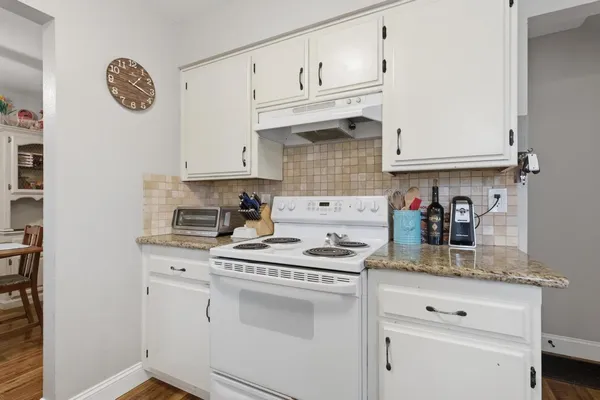 a kitchen with white cabinets and wooden floor