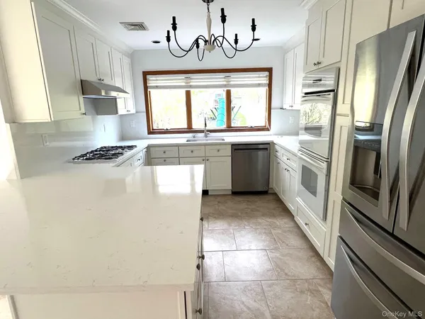 a kitchen with stainless steel appliances granite countertop a refrigerator a sink dishwasher a stove with wooden cabinets