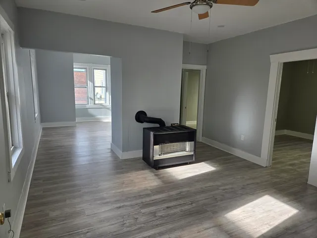 a hallway with wooden floor chandelier and windows