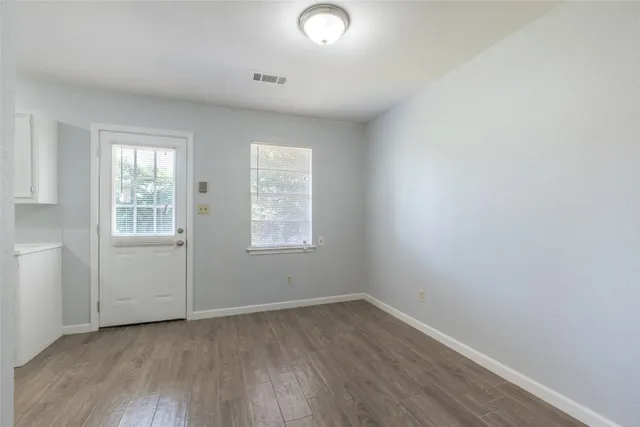 an empty room with wooden floor and windows