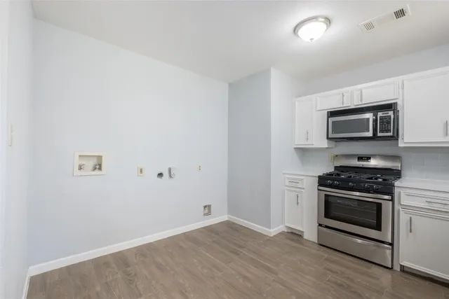 a kitchen with a stove a microwave and white cabinets