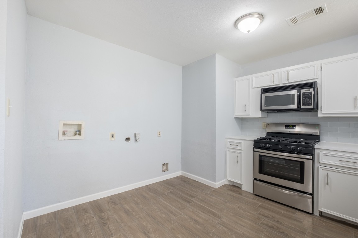 606 West Street Georgetown, TX 78626 - Photo 8 of 36 Kitchen featuring stainless steel appliances, white cabinets, light wood finished floors, and decorative backsplash