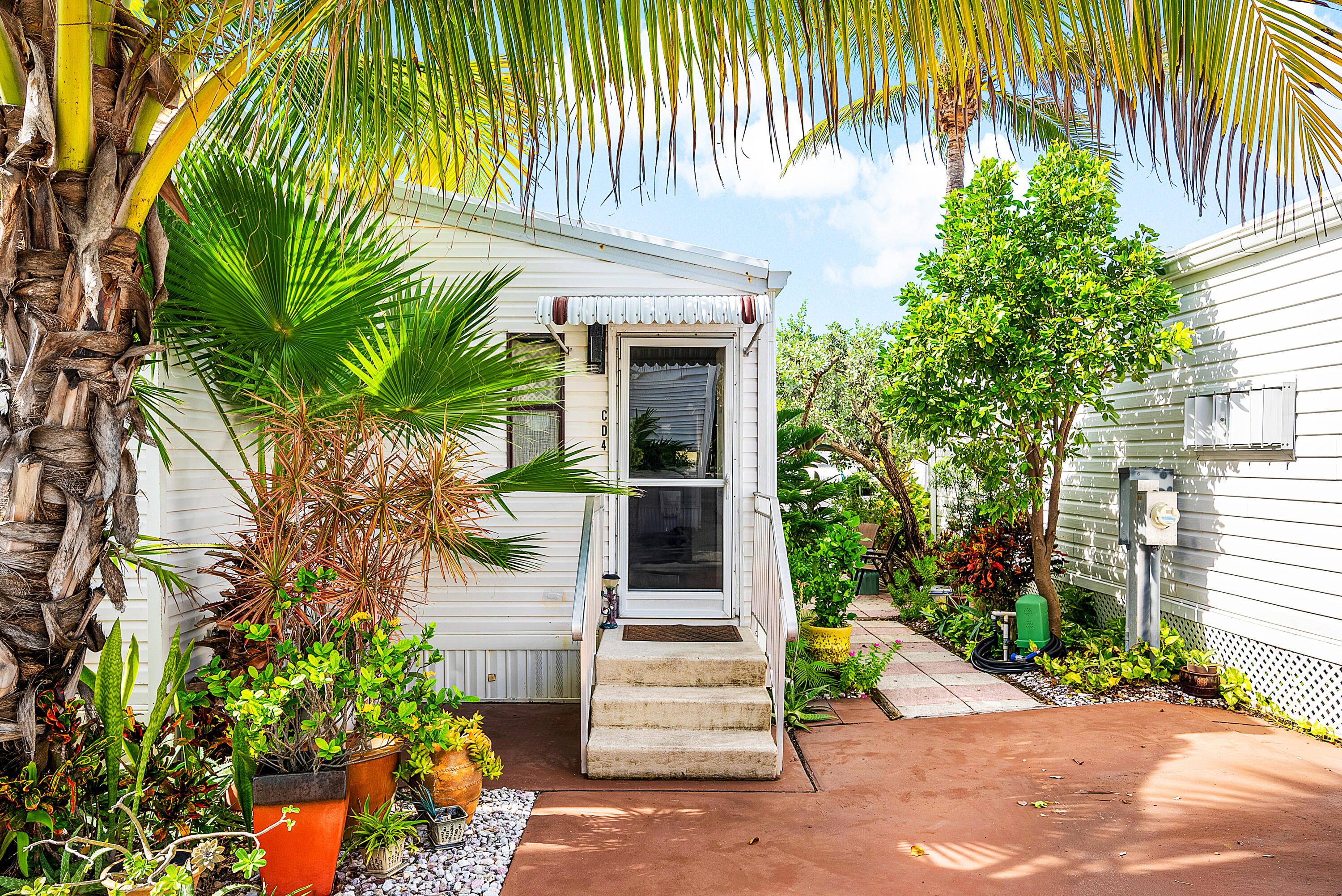 4 East Cedar Drive, Unit CD Briny Breezes, FL 33435 - Photo 2 of 28 a front view of a house with a garden