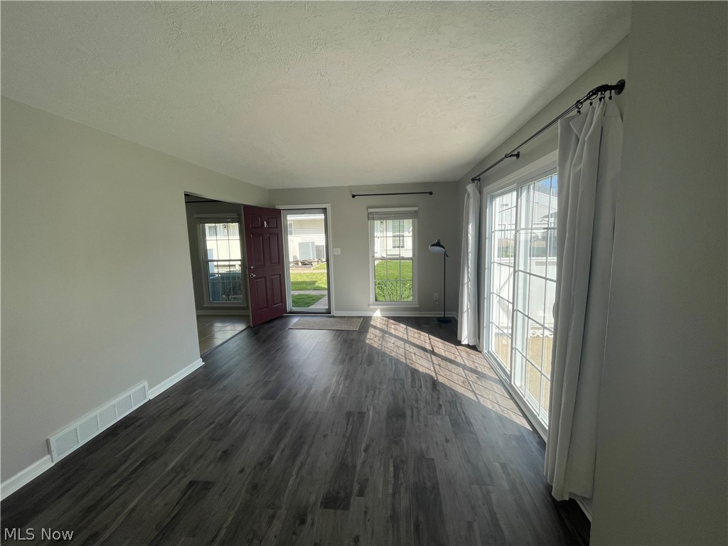 Unfurnished living room with a textured ceiling and dark LVT-style floors