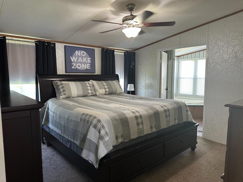 21516 Water Ridge Road Chandler, TX 75758 - Photo 11 of 40 a bedroom with a large bed and a chandelier