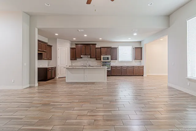 a view of kitchen kitchen with stainless steel appliances granite countertop a stove top oven a sink and white cabinets