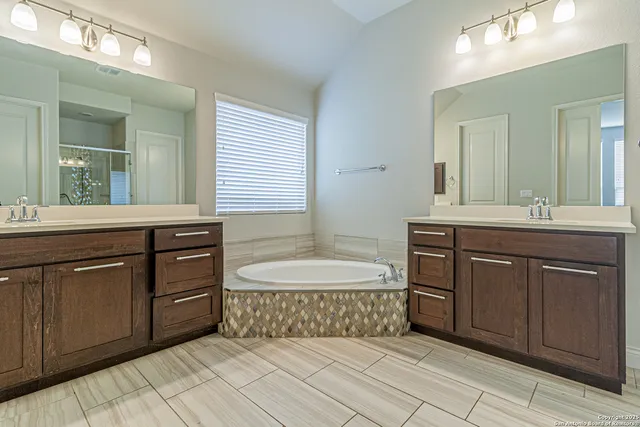 a spacious bathroom with a granite countertop double vanity sink mirror and bathtub