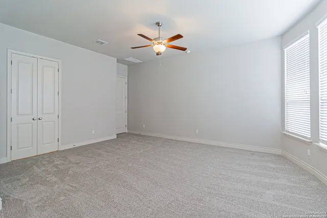 an empty room with windows and fan