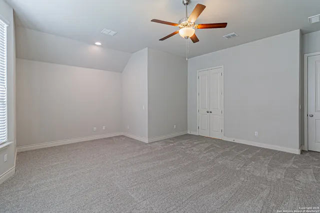an empty room with closet and a ceiling fan