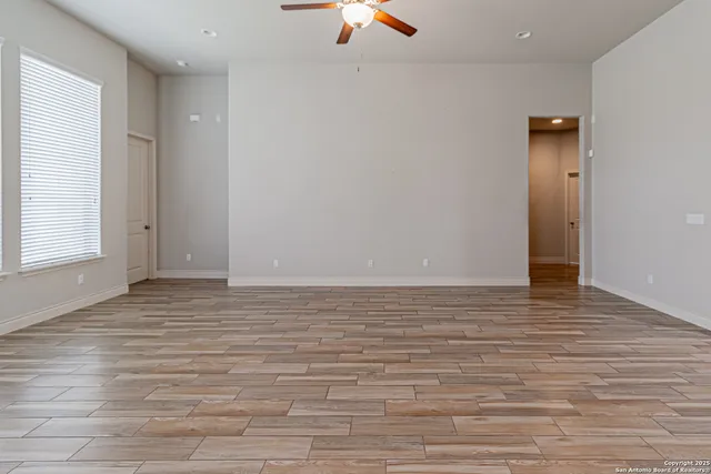 a view of an empty room with window ceiling fan and hardwood floor