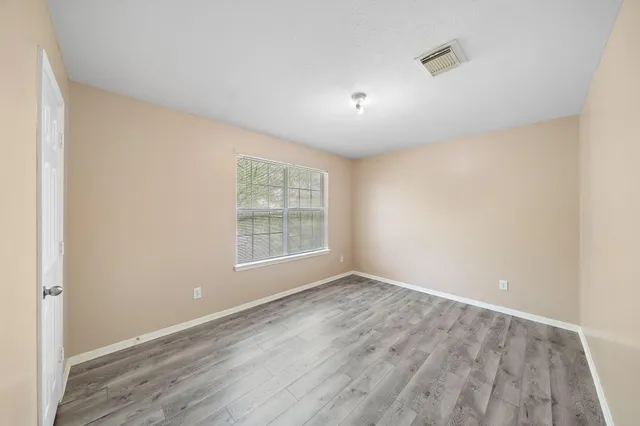 an empty room with wooden floor and windows