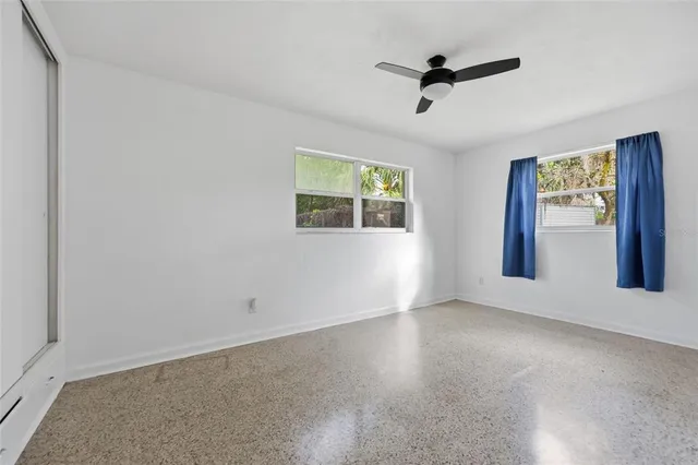 an empty room with windows and ceiling fan