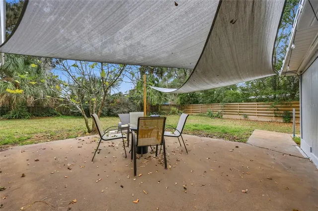 a view of a backyard with table and chairs under an umbrella with a small yard