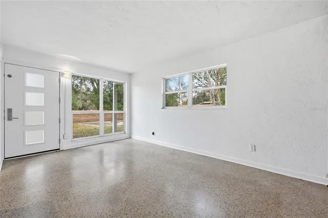 a view of an empty room with a window and wooden floor
