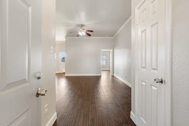 a view of an empty room with wooden floor and a ceiling fan