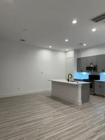 a view of kitchen with stainless steel appliances wooden floor and living room