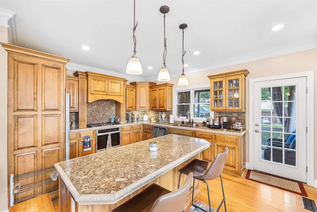 a kitchen with stainless steel appliances granite countertop table chairs and wooden floor