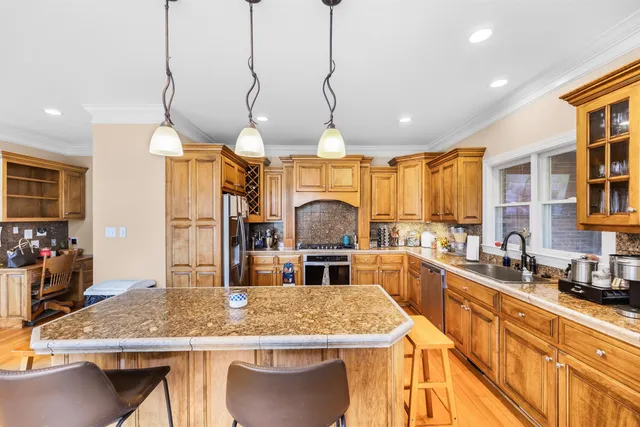 a kitchen with stainless steel appliances granite countertop a sink a stove counter space and a wooden floor