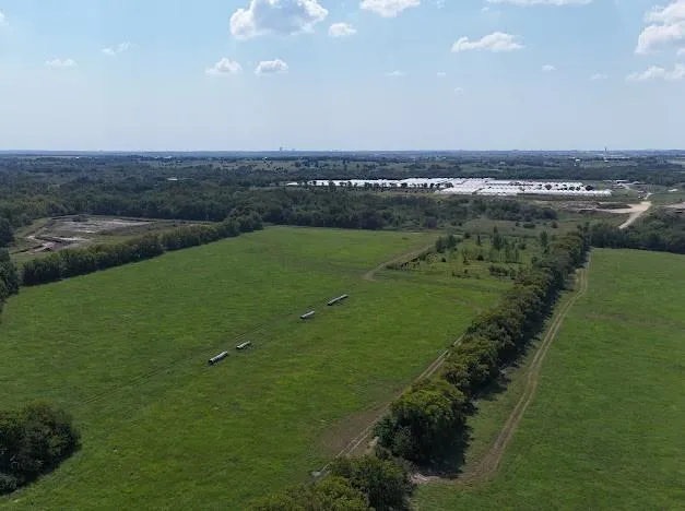 an aerial view of a houses with outdoor space and trees all around