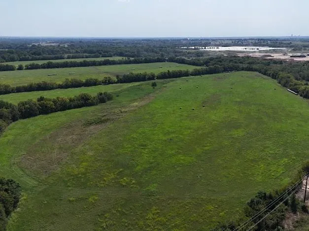 an aerial view of a houses with outdoor space and trees all around