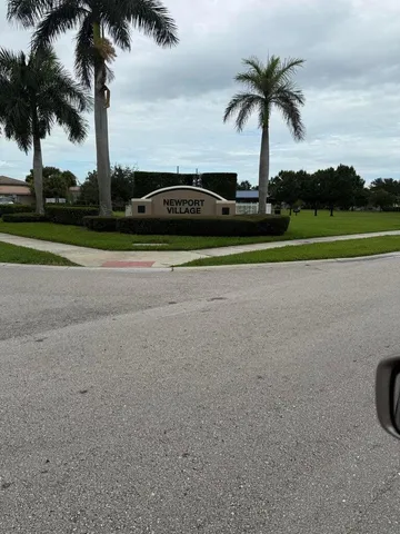 front view of house with a yard and palm trees