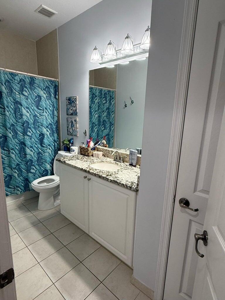 2891 Cedar Dunes Drive Port St. Lucie, FL 34953 - Photo 19 of 25 a bathroom with a granite countertop sink a toilet and a mirror