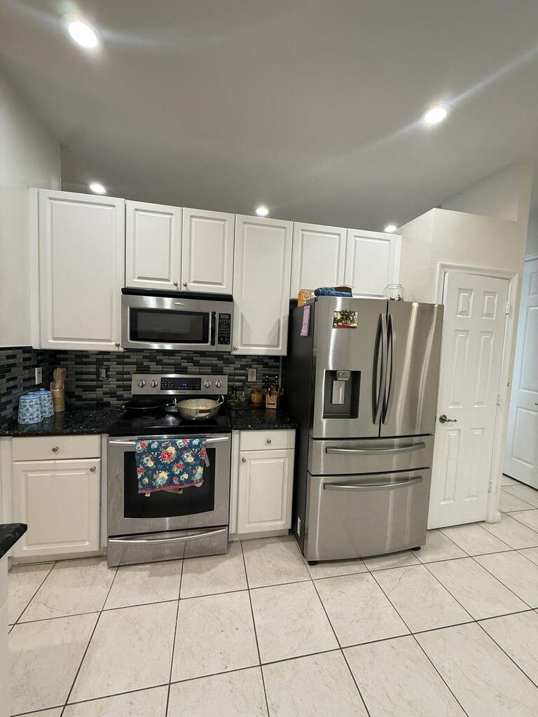 2891 Cedar Dunes Drive Port St. Lucie, FL 34953 - Photo 8 of 25 a kitchen with granite countertop a refrigerator and a stove top oven