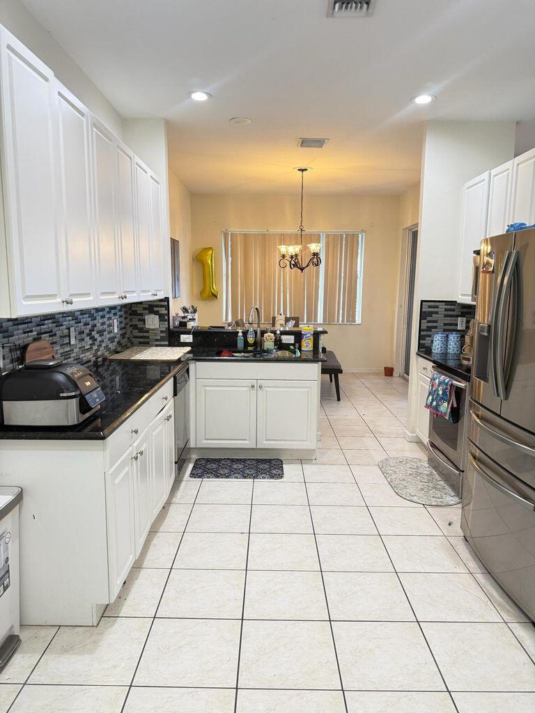 2891 Cedar Dunes Drive Port St. Lucie, FL 34953 - Photo 9 of 25 a kitchen with stainless steel appliances a sink stove and cabinets