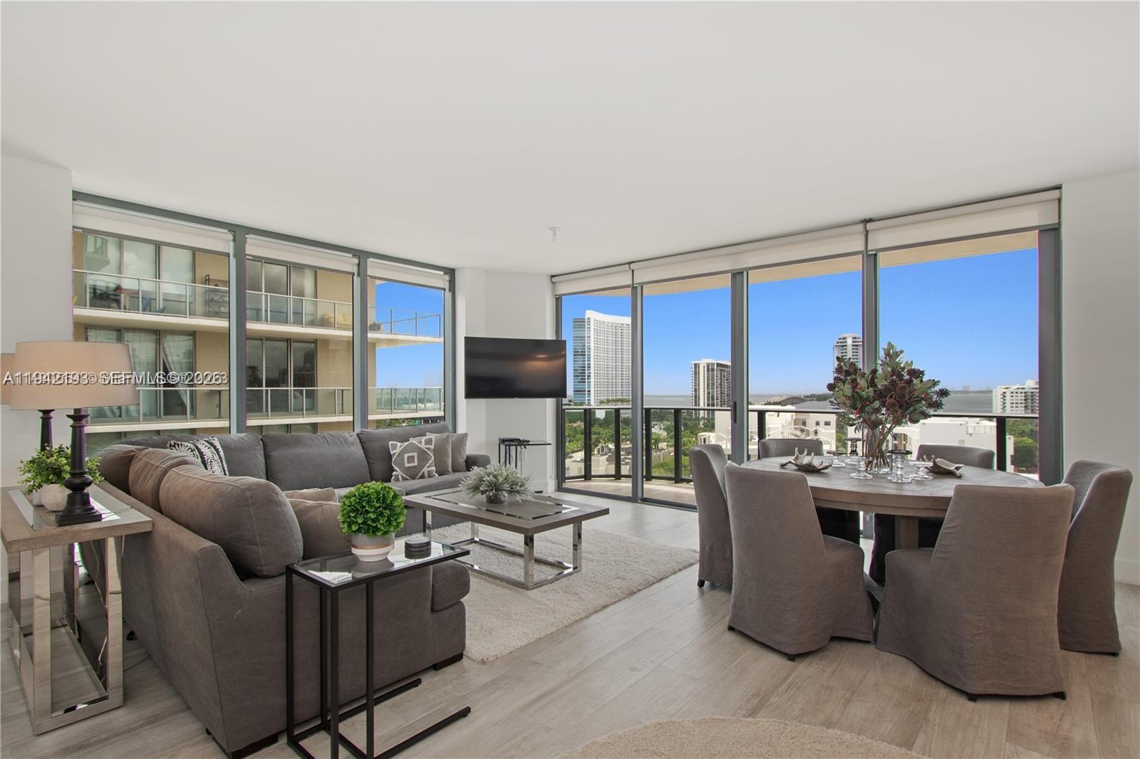 121 Northeast 34th Street, Unit 1008 Miami, FL 33137 - Photo 2 of 52 a living room with furniture a flat screen tv and a floor to ceiling window
