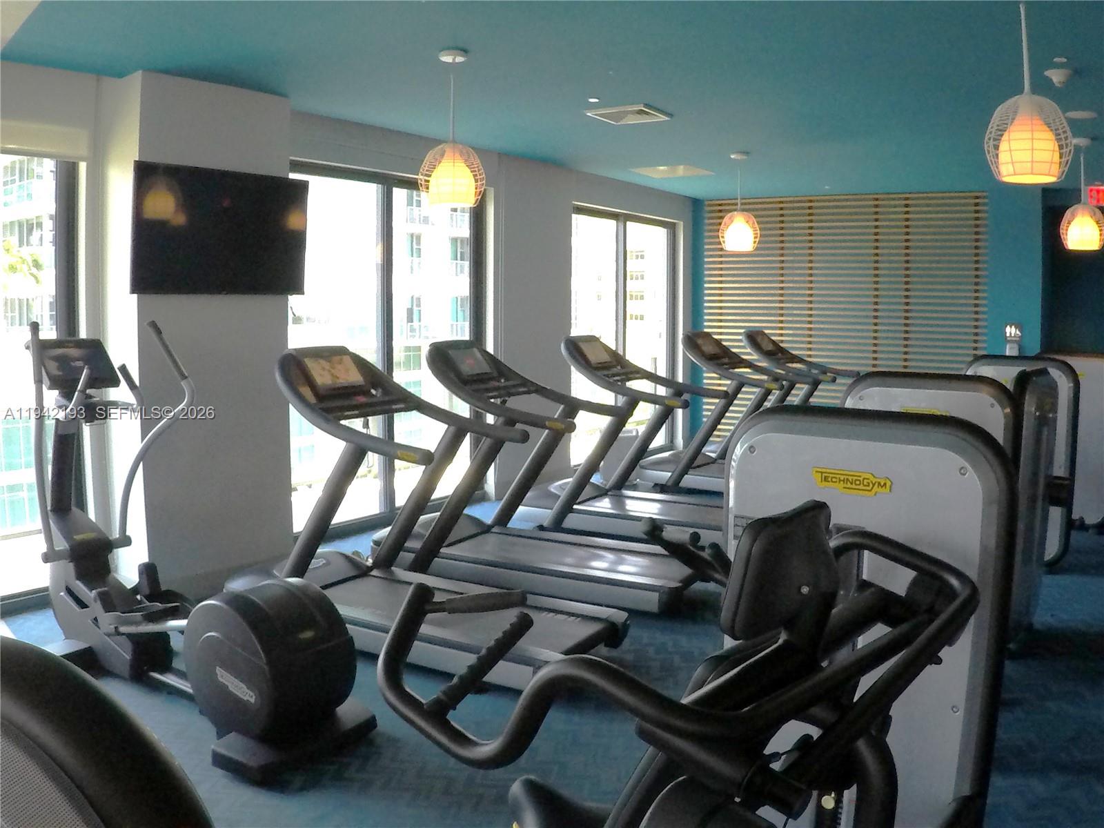 121 Northeast 34th Street, Unit 1008 Miami, FL 33137 - Photo 44 of 52 a room with gym equipment and a flat screen tv