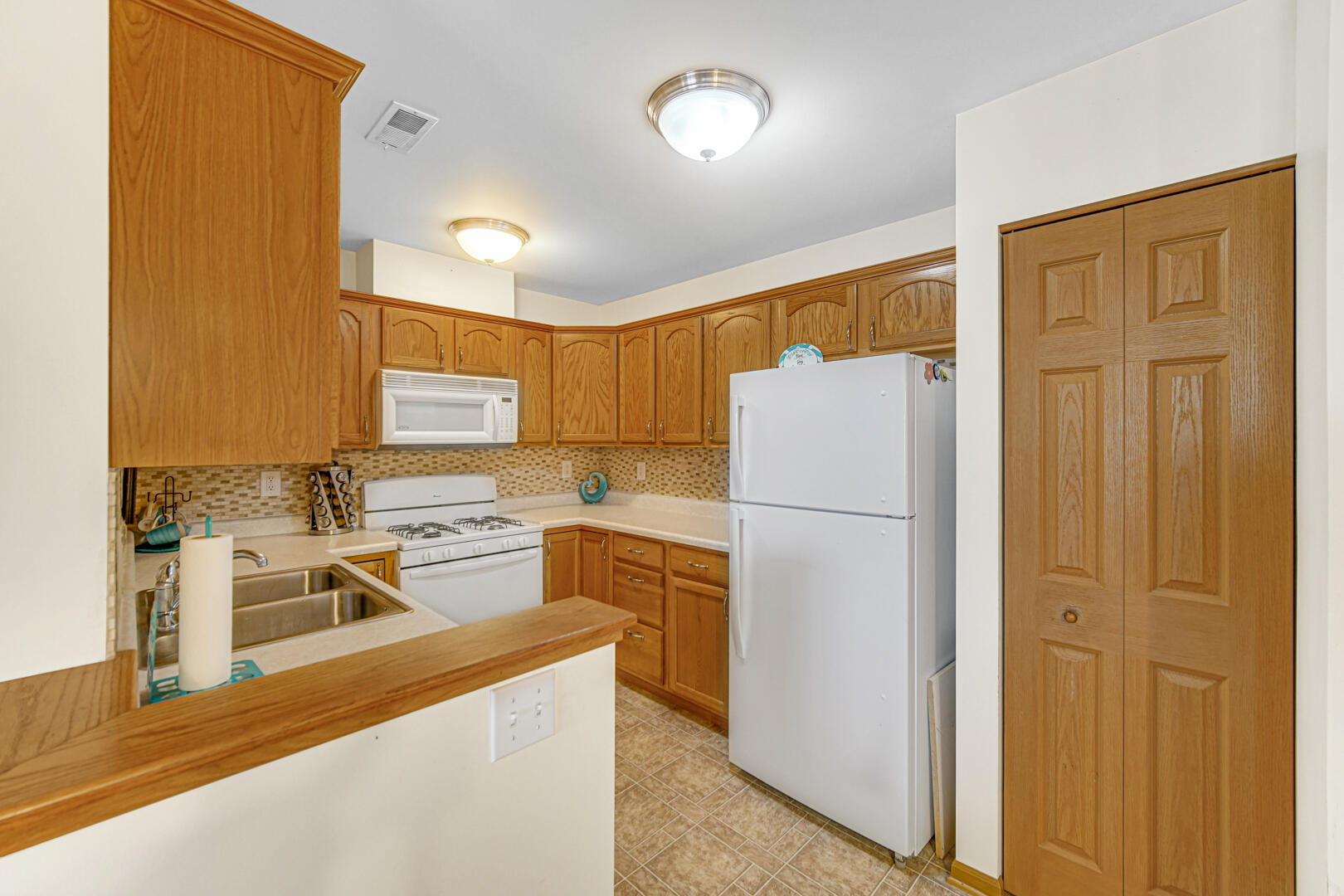 2007 West 75th Place, Unit 31 Merrillville, IN 46410 - Photo 10 of 17 a kitchen with a refrigerator a stove top oven a sink and dishwasher
