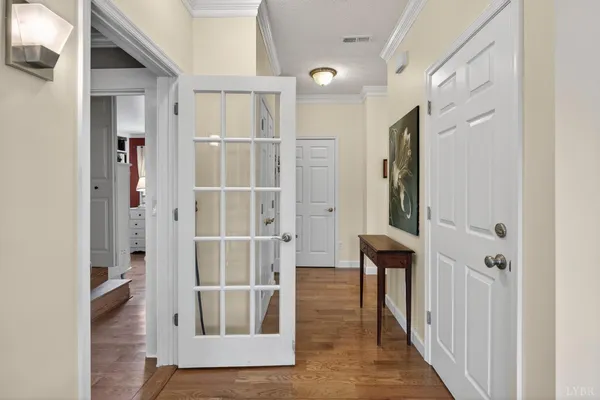 a view of a hallway with wooden floor and a bathroom