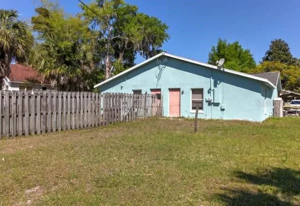 a view of a house with a small yard and a large tree