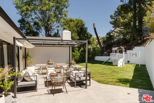 a view of a patio with table and chairs potted plants and large tree