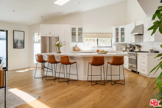 a kitchen with stainless steel appliances granite countertop a table and chairs in it