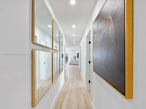 a view of a hallway with wooden floor and a bathroom