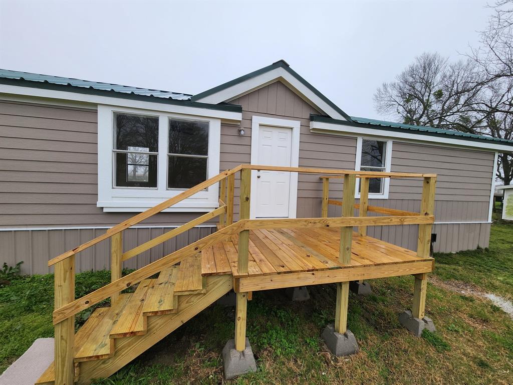 a view of a house with wooden deck and a chair