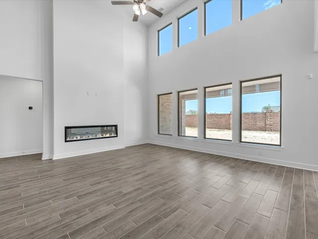 an empty room with chandelier fan and windows
