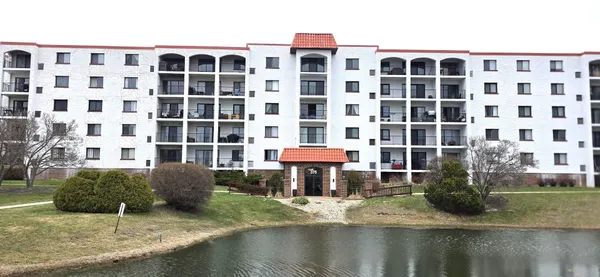 a front view of a building with a yard and lake view