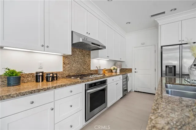 a open kitchen with stainless steel appliances granite countertop a sink and dishwasher with white cabinets