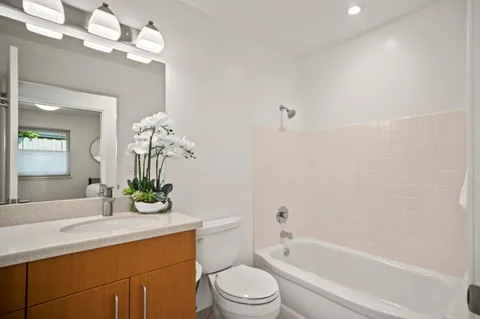 a bathroom with a granite countertop sink a toilet and bathtub