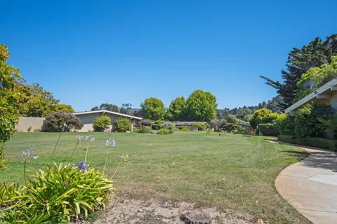 a view of swimming pool with seating space and trees in the background