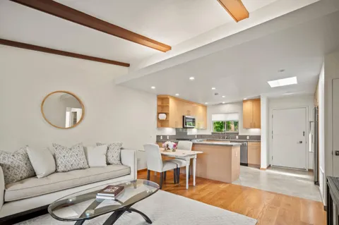 a living room with stainless steel appliances kitchen island granite countertop furniture and a wooden floor