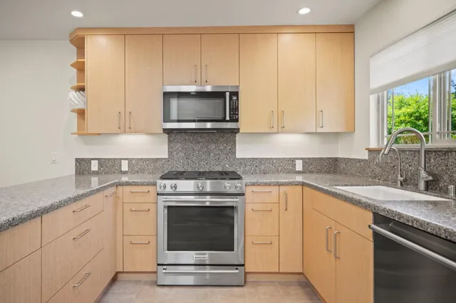 a kitchen with granite countertop white cabinets white stainless steel appliances and a sink