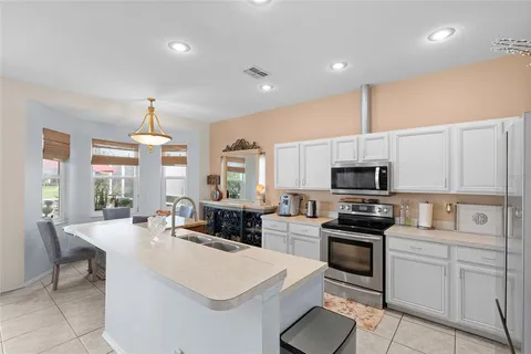 a kitchen with stainless steel appliances a stove a sink a microwave a refrigerator and white cabinets